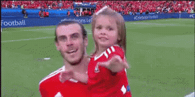 A Soccer Player Is Holding A Little Girl On His Shoulders On A Field . GIF