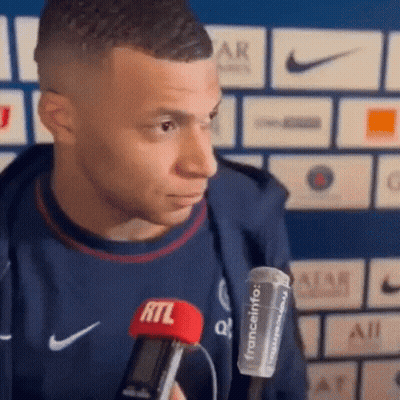 A Soccer Player Is Holding A Microphone In His Hand And Talking Into It . GIF