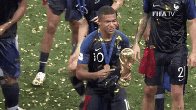 A Soccer Player Is Holding A Trophy And A Medal While His Teammates Celebrate . GIF