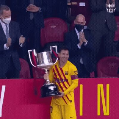 A Soccer Player Is Holding A Trophy In Front Of A Crowd While Wearing A Mask . GIF
