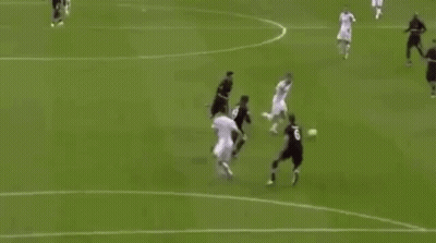 A Soccer Player Is Jumping In The Air To Score A Goal While A Goalkeeper Is Laying On The Field . GIF