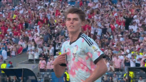 A Soccer Player Is Pointing At The Crowd While Wearing A Jersey With Flowers On It GIF