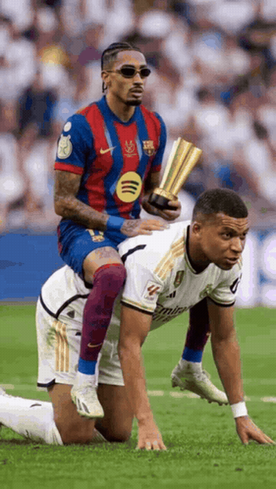 A Soccer Player Is Riding On The Back Of Another Soccer Player On A Field . GIF