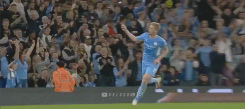 A Soccer Player Is Running In Front Of A Crowd On A Field . GIF