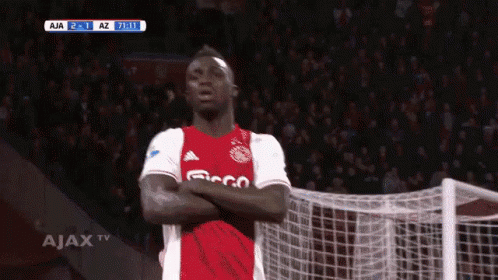 A Soccer Player Is Standing In Front Of A Goal With His Arms Crossed In Front Of A Ajax Tv Screen GIF
