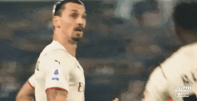 A Soccer Player Is Standing In Front Of Another Player On A Soccer Field . GIF