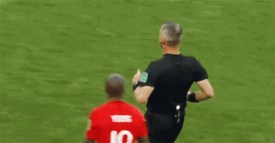 A Soccer Player Is Talking To A Referee On A Field . GIF