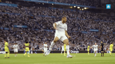 A Soccer Player Jumps In The Air In Front Of A Crowd With An Orange Sign In The Background GIF