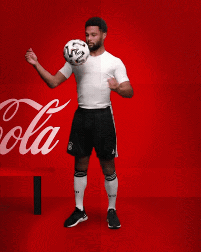 A Soccer Player Kicks A Soccer Ball In Front Of A Coca Cola Sign GIF