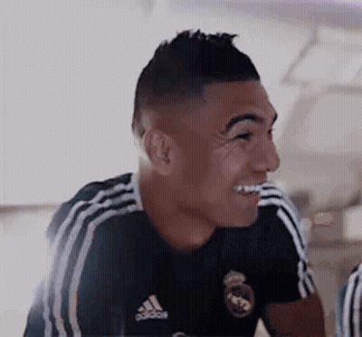 A Soccer Player Wearing A Black Adidas Jersey Is Smiling . GIF