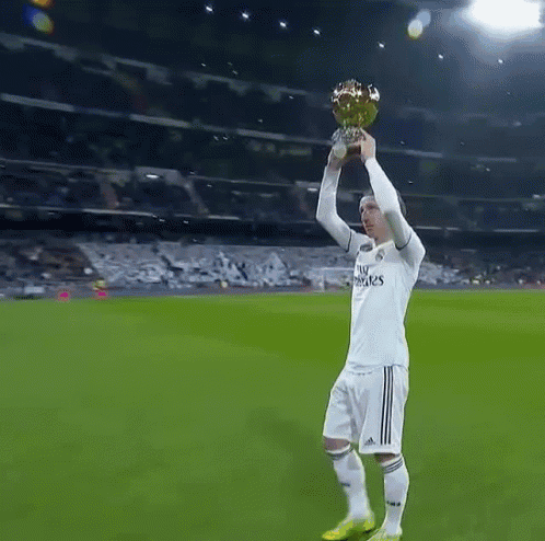 A Soccer Player Wearing A Fly Emirates Jersey Holds A Trophy In His Hand GIF