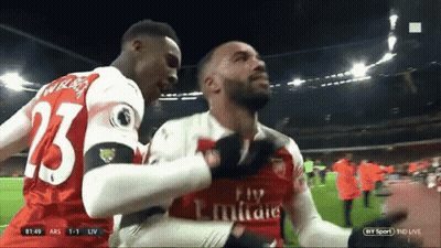 A Soccer Player Wearing A Fly Emirates Jersey Is Being Hugged By Another Player GIF