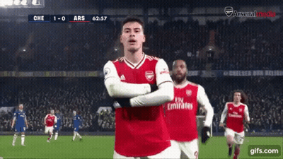 A Soccer Player Wearing A Fly Emirates Jersey Stands On The Field With His Arms Crossed GIF