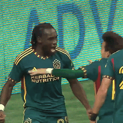 A Soccer Player Wearing A Green Herbal Nutrition Jersey Is Hugging Another Player GIF