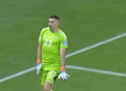 A Soccer Player Wearing A Green Jersey And Gloves Is Standing On A Field . GIF