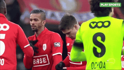 A Soccer Player Wearing A Green Jersey With The Letter S On It Is Talking To Another Player . GIF