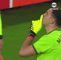 A Soccer Player Wearing A Green Shirt And Yellow Gloves Is Blowing A Whistle GIF