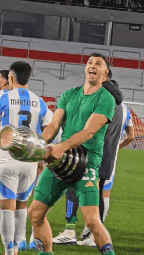 A Soccer Player Wearing A Martinez Jersey Holds A Trophy GIF