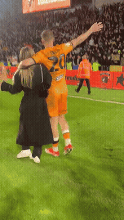 A Soccer Player Wearing A Number 20 Jersey Is Hugging A Woman GIF