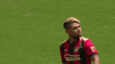 A Soccer Player Wearing A Red And Black Jersey Is Standing On The Field . GIF