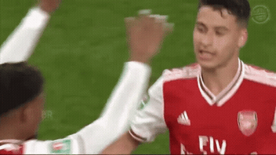 A Soccer Player Wearing A Red Fly Emirates Jersey Is Giving Another Player A High Five On The Field . GIF