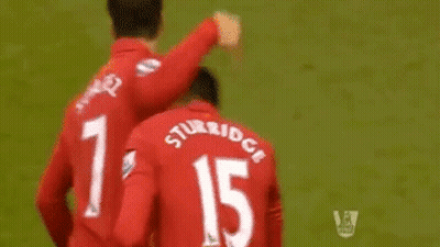 A Soccer Player Wearing A Red Jersey That Says Standard Chartered Is Giving Another Player A High Five GIF