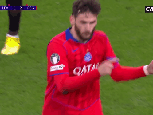 A Soccer Player Wearing A Red Qatar Jersey Is Pointing At Something GIF
