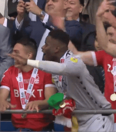 A Soccer Player Wearing A Sky Sports Shirt Stands In The Crowd GIF