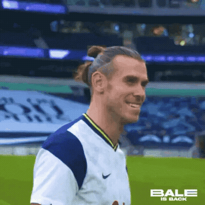 A Soccer Player Wearing A White And Blue Jersey Is Smiling On A Field . GIF