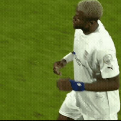 A Soccer Player Wearing A White Jersey And Blue Wristband Is Running On The Field . GIF