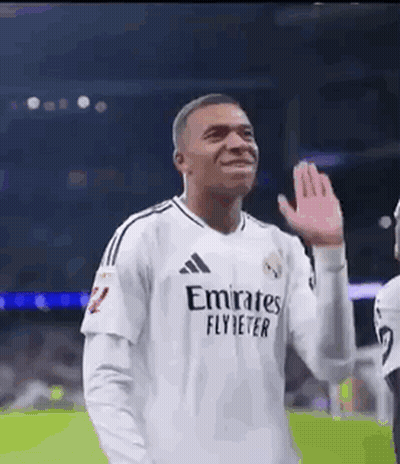 A Soccer Player Wearing A White Jersey With Emirates Fly Better On It Is Waving His Hand . GIF