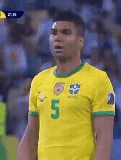 A Soccer Player Wearing A Yellow And Green Jersey With The Number 5 On It Is Standing In Front Of A Crowd . GIF