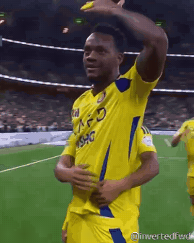 A Soccer Player Wearing A Yellow Jersey With A Blue Stripe On The Sleeves GIF
