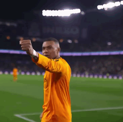A Soccer Player Wearing An Orange Jersey Is Giving A Thumbs Up GIF