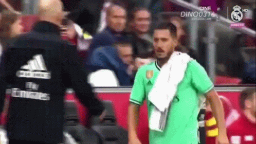 A Soccer Player With A Towel Around His Neck Is Talking To Another Man GIF