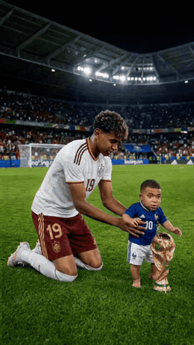 a soccer player with the number 19 on his jersey is kneeling down with a baby