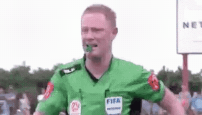 A Soccer Referee Is Wearing A Green Shirt With A Fifa Logo On It And Has A Green Object In His Mouth . GIF