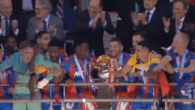 A Soccer Team Is Holding A Trophy In Front Of A Crowd Of People . GIF