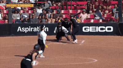 A Softball Game Is Being Played In Front Of A Geico Sign GIF