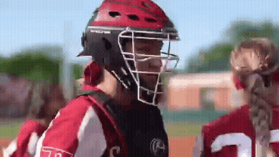 A Softball Player Wearing A Helmet And A Catcher 'S Mask Is Talking To Another Player On The Field . GIF