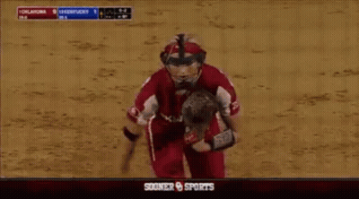 A Softball Player Wearing A Helmet And Glove Runs Towards A Scoreboard That Says Sooner Sports GIF