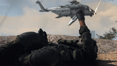 A Soldier Laying On The Ground With A Helicopter Flying In The Background With The Letters Usmc On It GIF