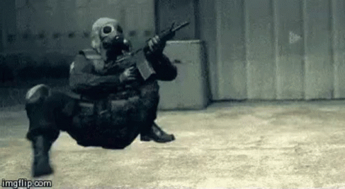 A Soldier Wearing A Gas Mask Is Holding A Gun In A Warehouse . GIF
