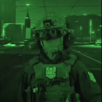 A Soldier Wearing A Helmet And Goggles Is Standing In A Dark Street At Night . GIF