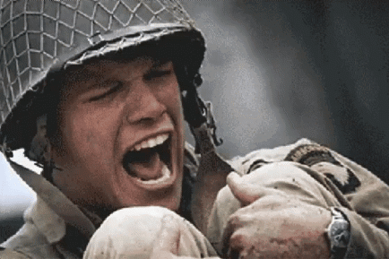 A Soldier Wearing A Helmet Is Holding A Baby In His Arms . GIF