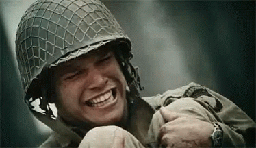 A Soldier Wearing A Helmet Is Smiling While Holding Another Soldier . GIF