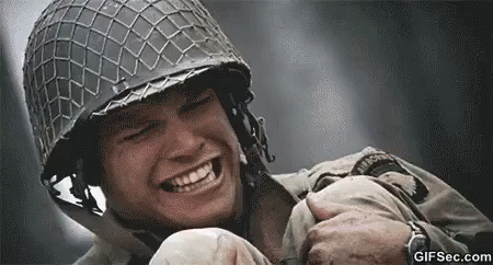 A Soldier Wearing A Helmet Is Smiling While Holding Another Soldier 'S Arm . GIF