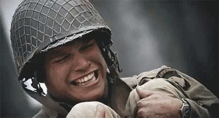 A Soldier Wearing A Helmet Is Smiling While Holding Another Soldier 'S Arm . GIF