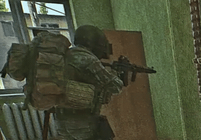 A Soldier With A Backpack Holding A Gun In A Room GIF