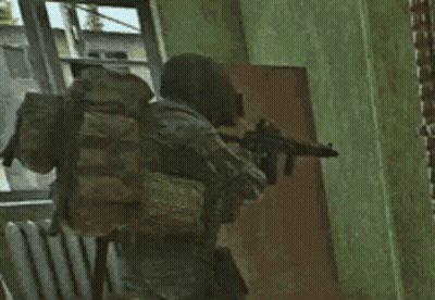 A Soldier With A Backpack Is Holding A Gun In Front Of A Door . GIF